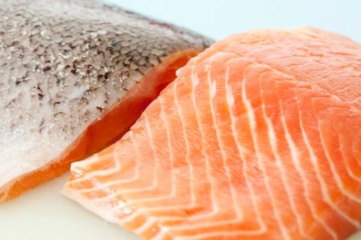 Two fresh uncooked salmon steaks one facing up showing the texture of the flesh and one facing down showing the skin for a healthy gourmet seafood dinner