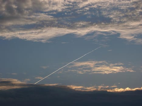 clouds and sky with a vapour trail from a passing jet aircraft