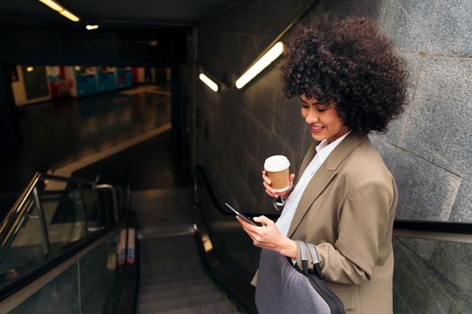 happy business woman checking phone on the escalator of the subway station, concept of urban lifestyle and public transport, copy space for text
