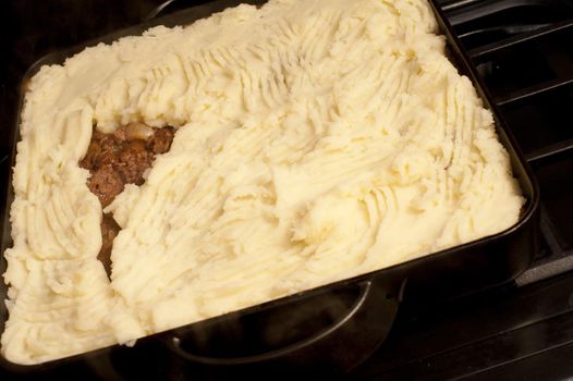 Baking dish with Shepherds pie made of minced or chopped meat, usually beef, topped with a crust of mashed potato