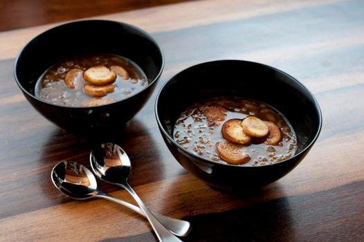 Two bowls of steaming hot french brown onion soup in bowls served as a starter and appetizer on a cold winter day