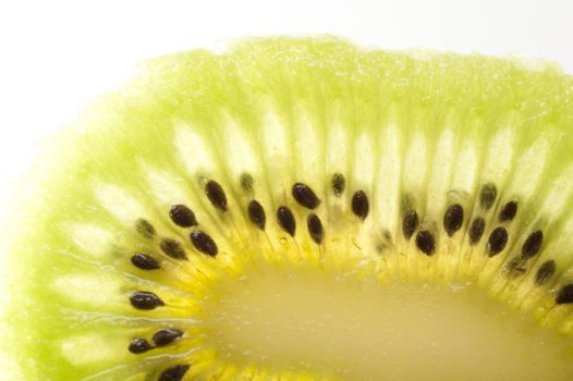 Macro detail of a slice peeled kiwifruit showing the interesting natural pattern of the juicy green flesh and pips on a white background