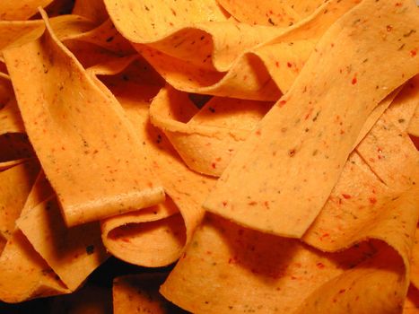 Seasoned Italian pasta ribbons or noodles in a full frame background texture in warm light