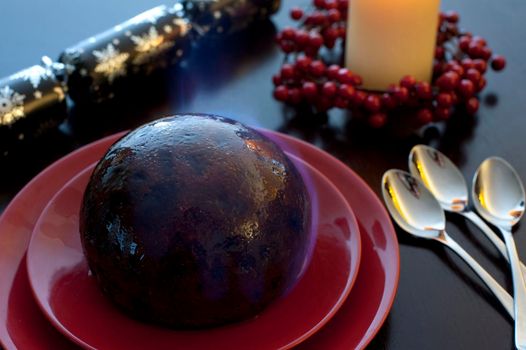 Flaming rich fruity steamed Christmas pudding doused in brandy and set alight served at the table