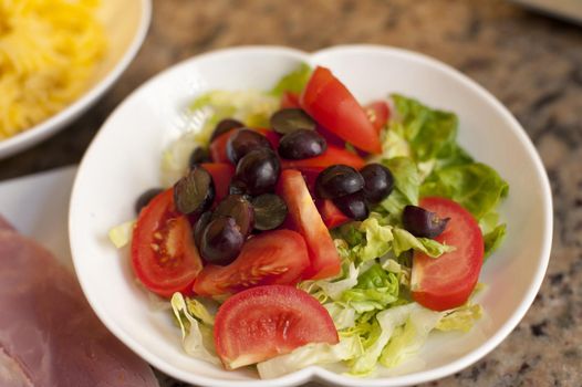 Fresh tomato and lettuce salad topped with black grapes for a tasty appetizer or accompaniment to lunch