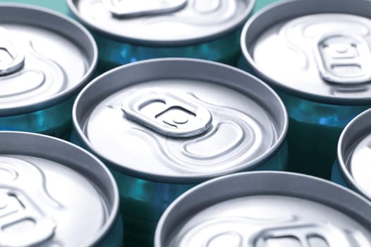 Close up view of plain silver ring pulls on closely arranged beverage cans with focus to one can in the centre