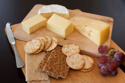 Cheese platter of assorted cheeses served with crispbread, wheat crackers, water biscuits and grapes
