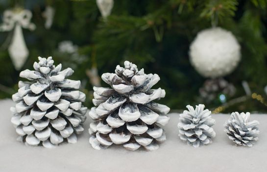 Cones in the snow on the background of a Christmas tree
