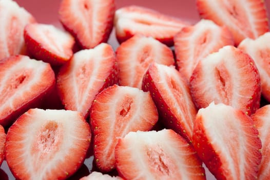 Halved strawberries carefully arranged to show the texture of the flesh during preparation of a delicious fruit dessert