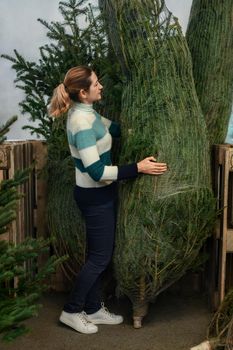 A woman buying a Christmas tree wrapped in a net