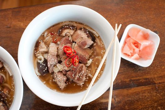 Japanese ramen, a tradional meal of noodles in a broth garnished with cooked pork and vegetables, overhead view