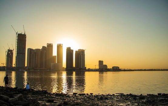 Sunrise in Jadaf area of Dubai, view of Dubai creek Harbor construction of which is partially completed. Some men fishing. Outdoors