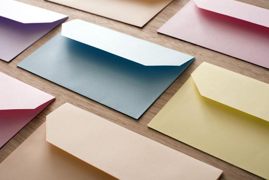 Rows of colorful paper blank Easter cards envelopes over wooden table, invitation concept background
