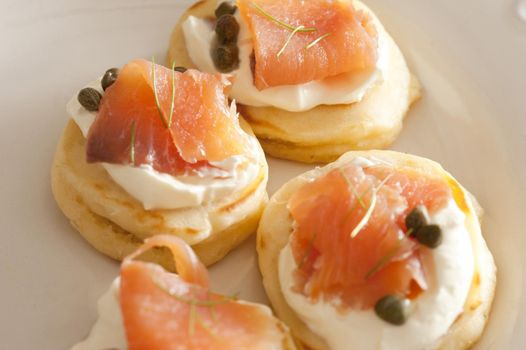 Selective focus cropped close up on lox biscuit snacks topped with capers and white sour cream or cheese
