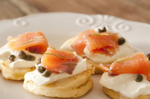 a plate of smoked salmon and cream cheese blini canapes