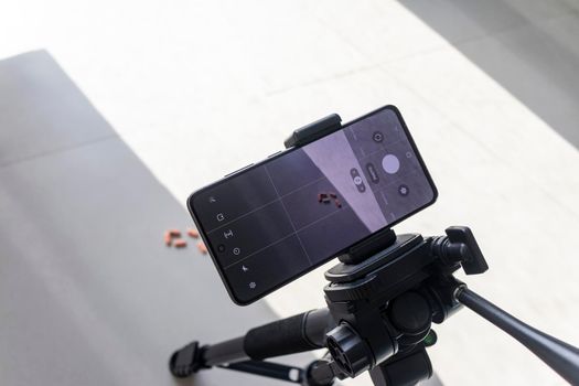 Close up shot of a phone on tripod capturing medicine on the surface