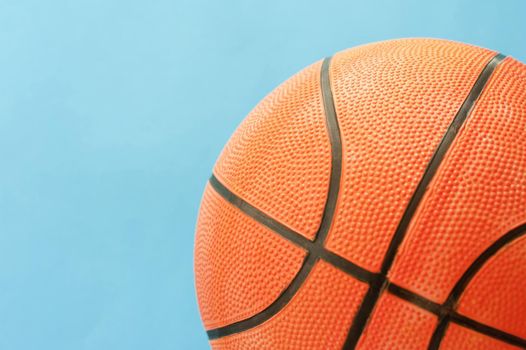 Close up Textured Orange Basketball Ball with Black Lines Isolated on a Sky Blue Background
