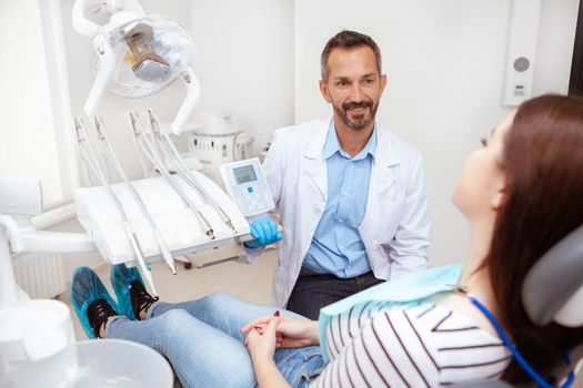 Attractive friendly male dentist talking to a female patient during dental checkup