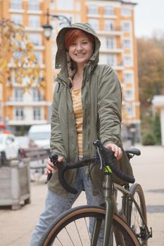 Vertical portrait of a beautiful cheerful woman walking with her bike in city center