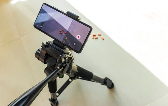 Close up shot of a phone on tripod capturing medicine on the surface