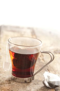 Brewing tea in a glass mug with a teabag steeping in boiling water for a refreshing drink, close up with copyspace