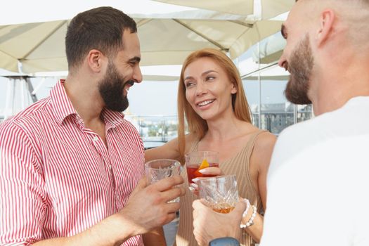 Beautiful woman talking to her male friends over drinks on a rooftop party