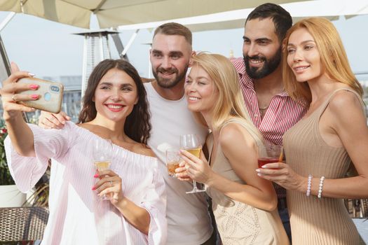 Happy young friends taking selfies during rooftop party