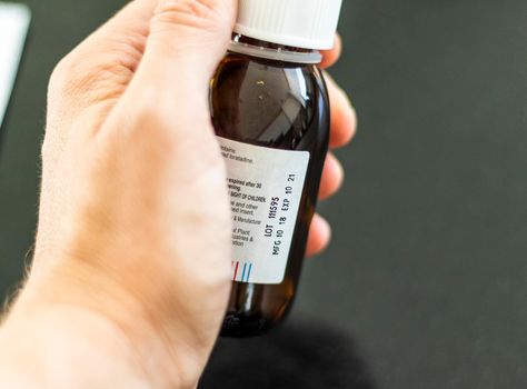 Close up shot of a hand holding a bottle with medicine with expired date