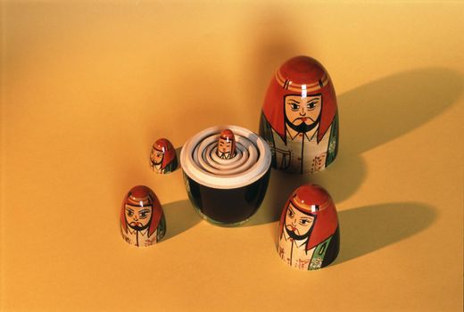 Set of nesting Russian Babushka dolls with the bottom halves stacked and heads surrounding them on yellow