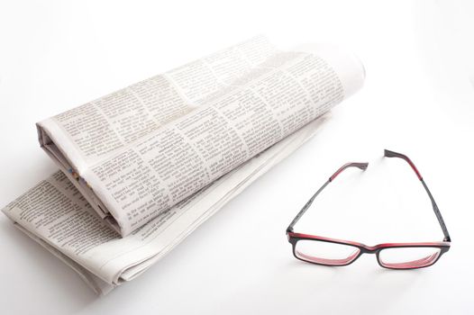 Reading newspapers concept with a pair of glasses and two folded fresh newspapers on white table surface in close-up