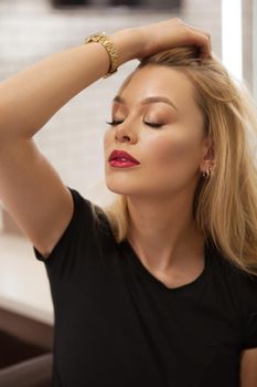 Vertical portrait of a gorgeous young woman with red lips playing with her hair