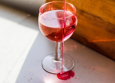 Shot of a red liquid being poured in to the wine glass.