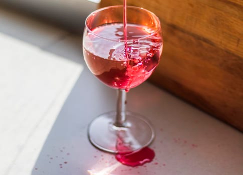 Shot of a red liquid being poured in to the wine glass.