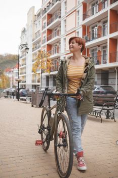 Vertical full length shot of a young woman walking city streets with her bicycle