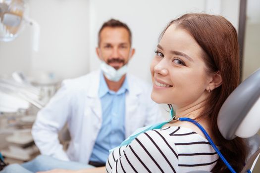 Charming happy woman smiling to the camera, sitting in dental chair after teeth examination