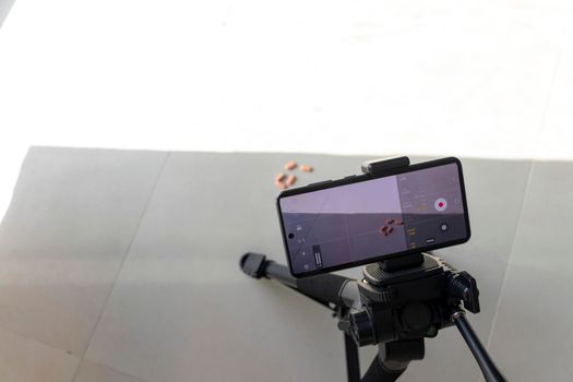 Close up shot of a phone on tripod capturing medicine on the surface