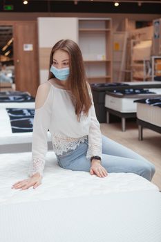 Vertical shot of a woman in protective face mask shopping for orthopedic bed