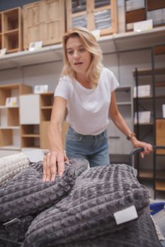 Selective focus on soft cushions mature housewife is buying at furnishings store