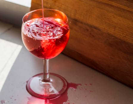 Shot of a red liquid being poured in to the wine glass.