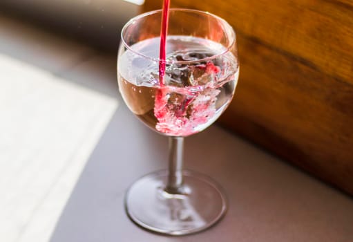 Shot of a red liquid being poured in to the wine glass