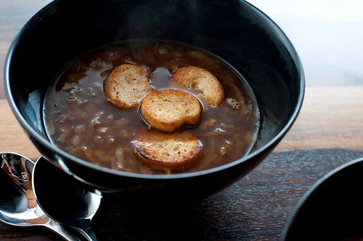 Crisp golden fried croutons floating in a bowl of brown French onion soup