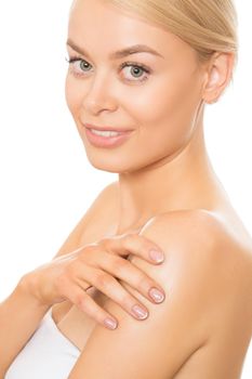 Vertical close up of a naturally beautiful young woman smiling joyfully to the camera applying body cream on her shoulder isolated skincare spa treatment beauty femininity treatment elegance sensuality