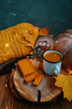 Autumn composition for posters. Carrot cake, pumpkin juice, fall leaves, sweater, scarf, pumpkin, postcard with Harry Potter and garland on wooden background. Bishkek, Kyrgyzstan - November 1, 2019.