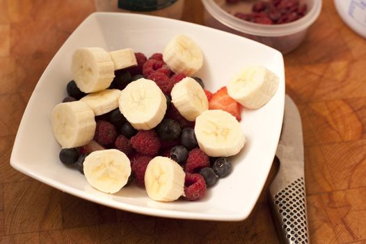 Bowl with a mix of fresh nutritious fruits as bananas, blueberries, raspberries and strawberries, high-angle close-up