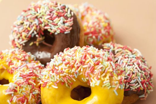 Doughnut assortment with colorful ring donuts glazed with chocolate, lemon and orange icing covered in multicolored candy sprinkles