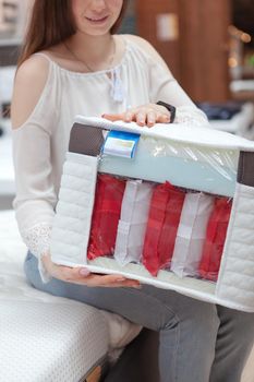 Vertical cropped shot of a female customer holding orthopedic mattress sample