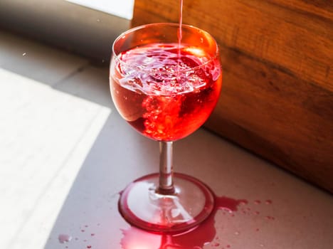 Shot of a red liquid being poured in to the wine glass.