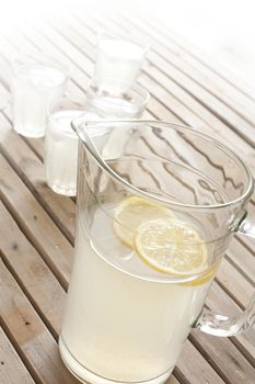 Refreshing fruity summer drinks with fresh homemade lemonade in a jug with tumblers on a wooden picnic table outdoors
