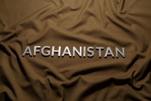 the word afghanistan laid with silver metal letters on tan khaki canvas fabric