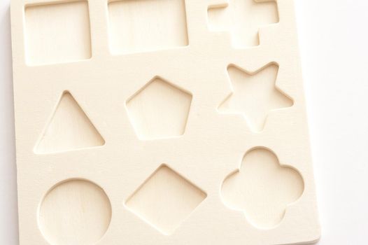 Wooden board puzzle with nine different basic cut out shapes into which to fit matching blocks for educating children